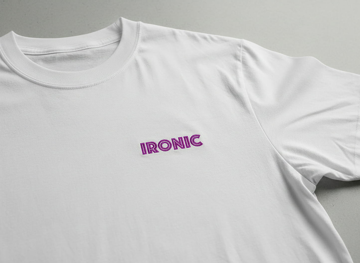 White t-shirt with 'IRONIC' logo on a gray background